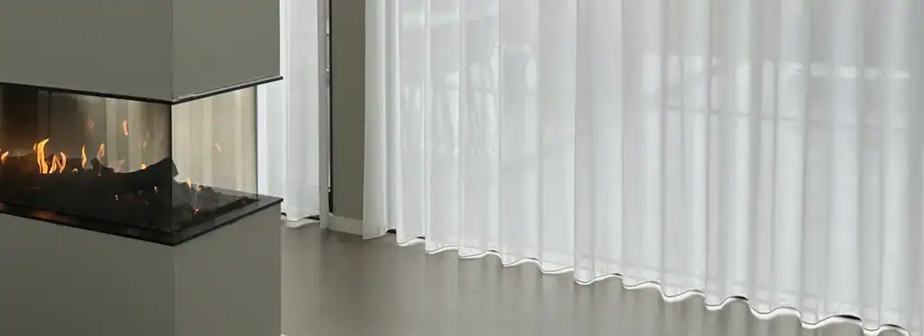 Hvidt transparent gardin i sommerhus med pejsehygge